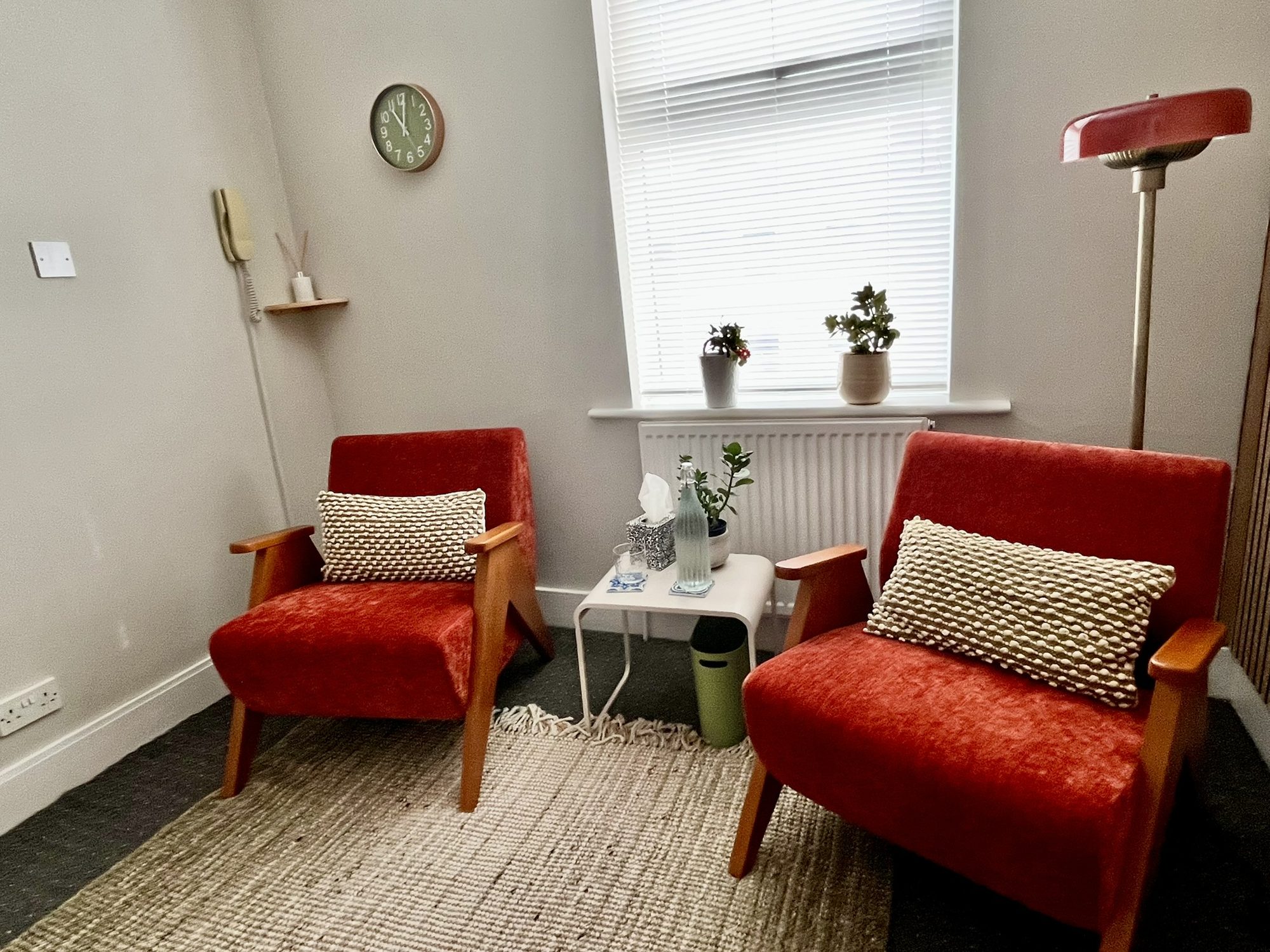 Therapy room with two red armchairs, a side table and a window at Hackney Therapy House