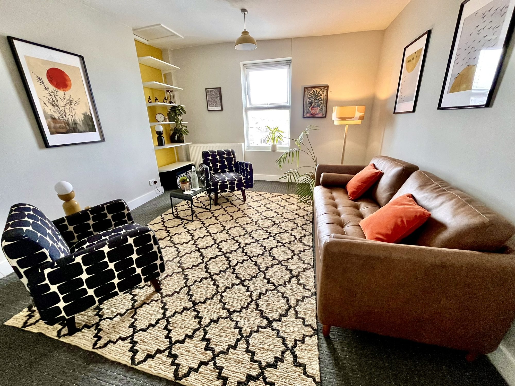 Large therapy room with leather sofa and patterned armchairs at Hackney Therapy House, Dalston