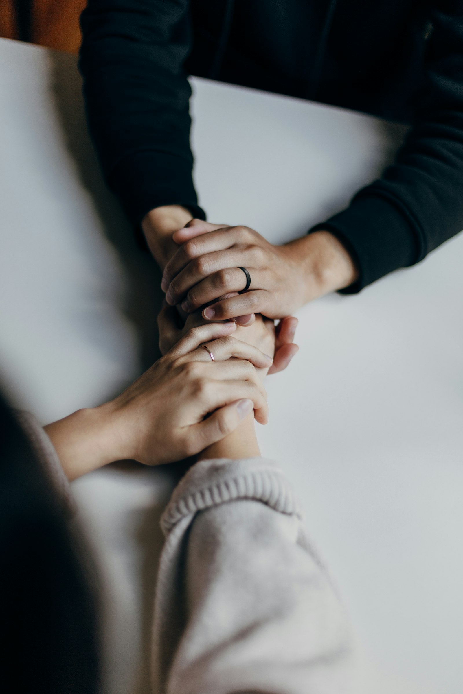 Two people holding hands across a table in a supportive conversation